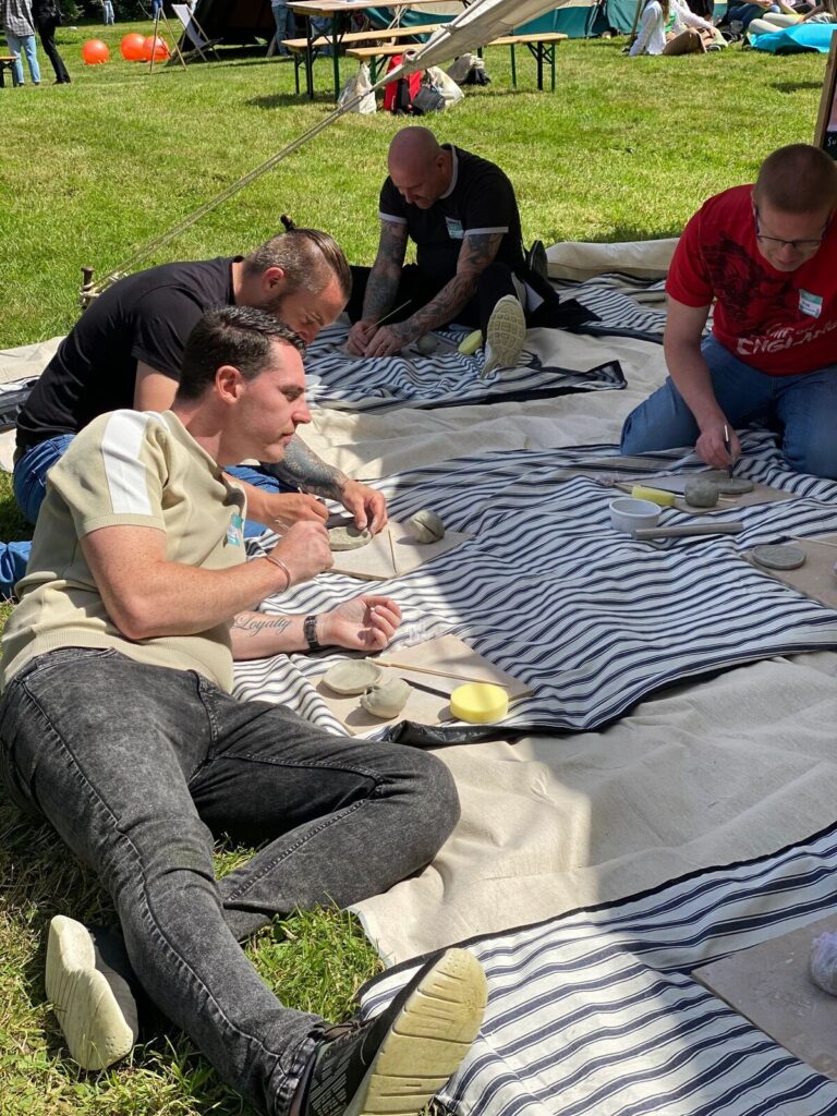 A team making pottery together on blankets outdoors