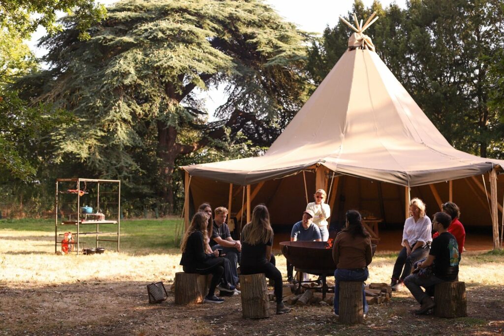 A team gathered under a tipi on the farm